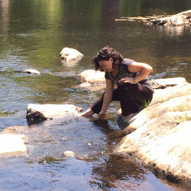 Raena Wilson feeling flow with the river, soaking in the sun, grounding with the stone and land.